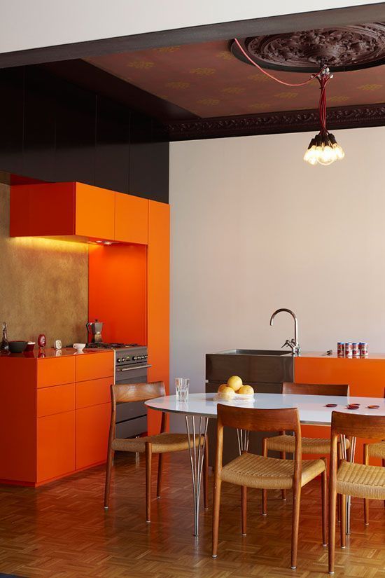 Orange cabinets in modern black and white kitchen with rustic floor and ceiling