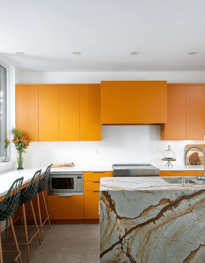 Bright orange minimal kitchen cabinets and marble block kitchen island with rust veins in modern white kitchen