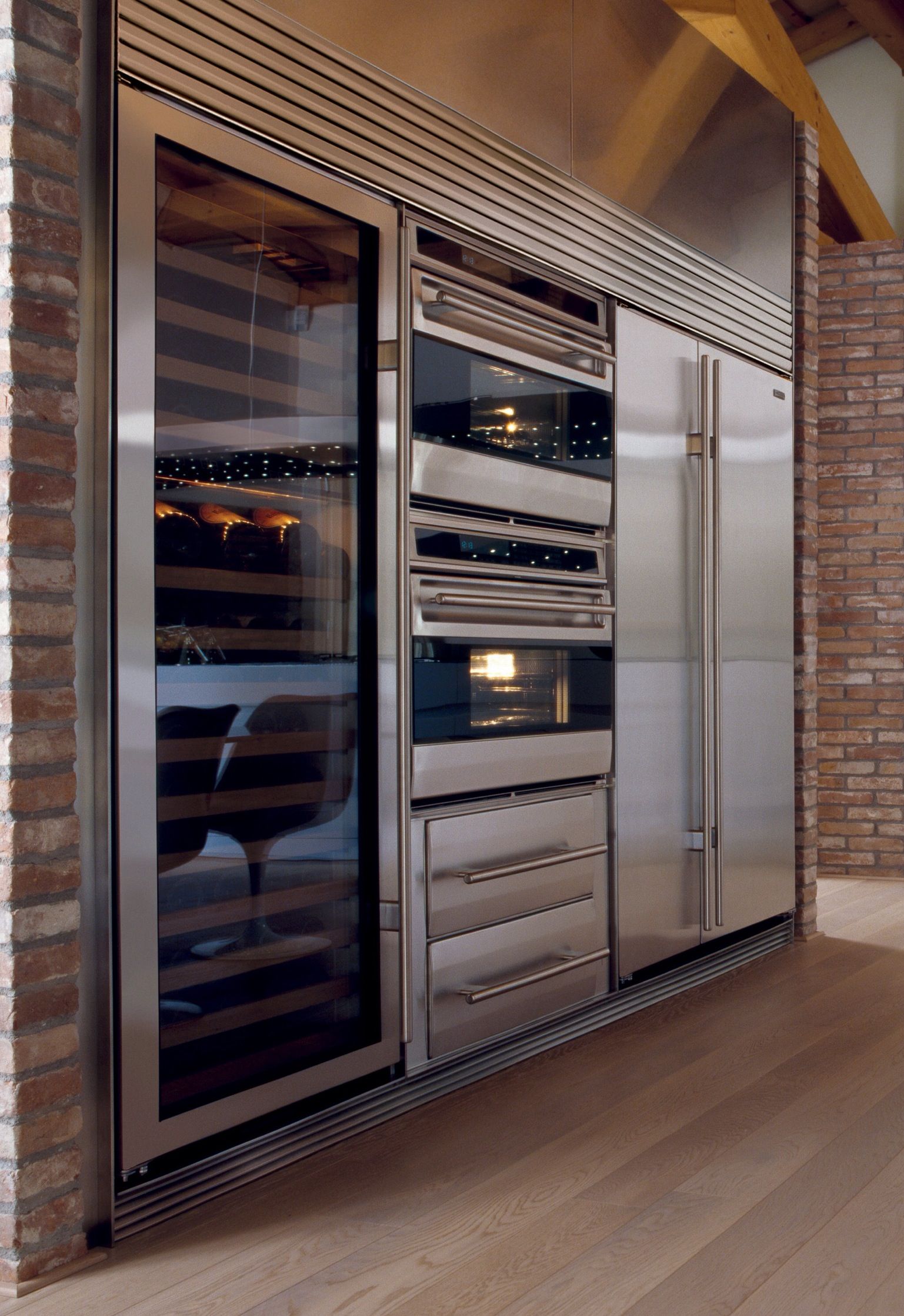 brick wall featuring stainless steel appliances like wine fridge, fridge and cookers