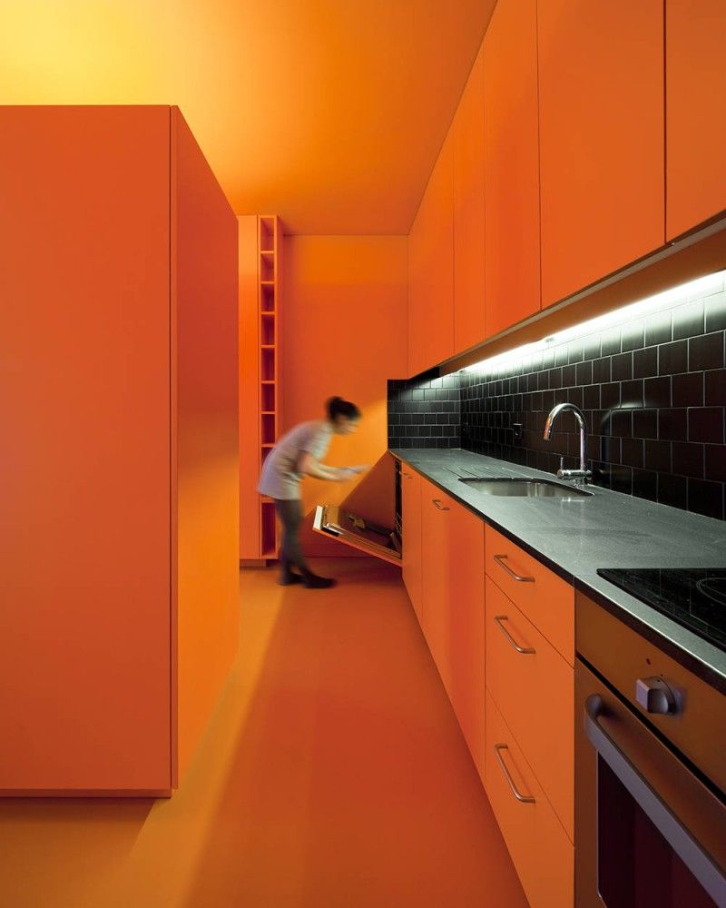 monochromatic orange kitchen, orange cabinets, floor, ceiling, lighting and black countertop and subway tile backsplash. modern.
