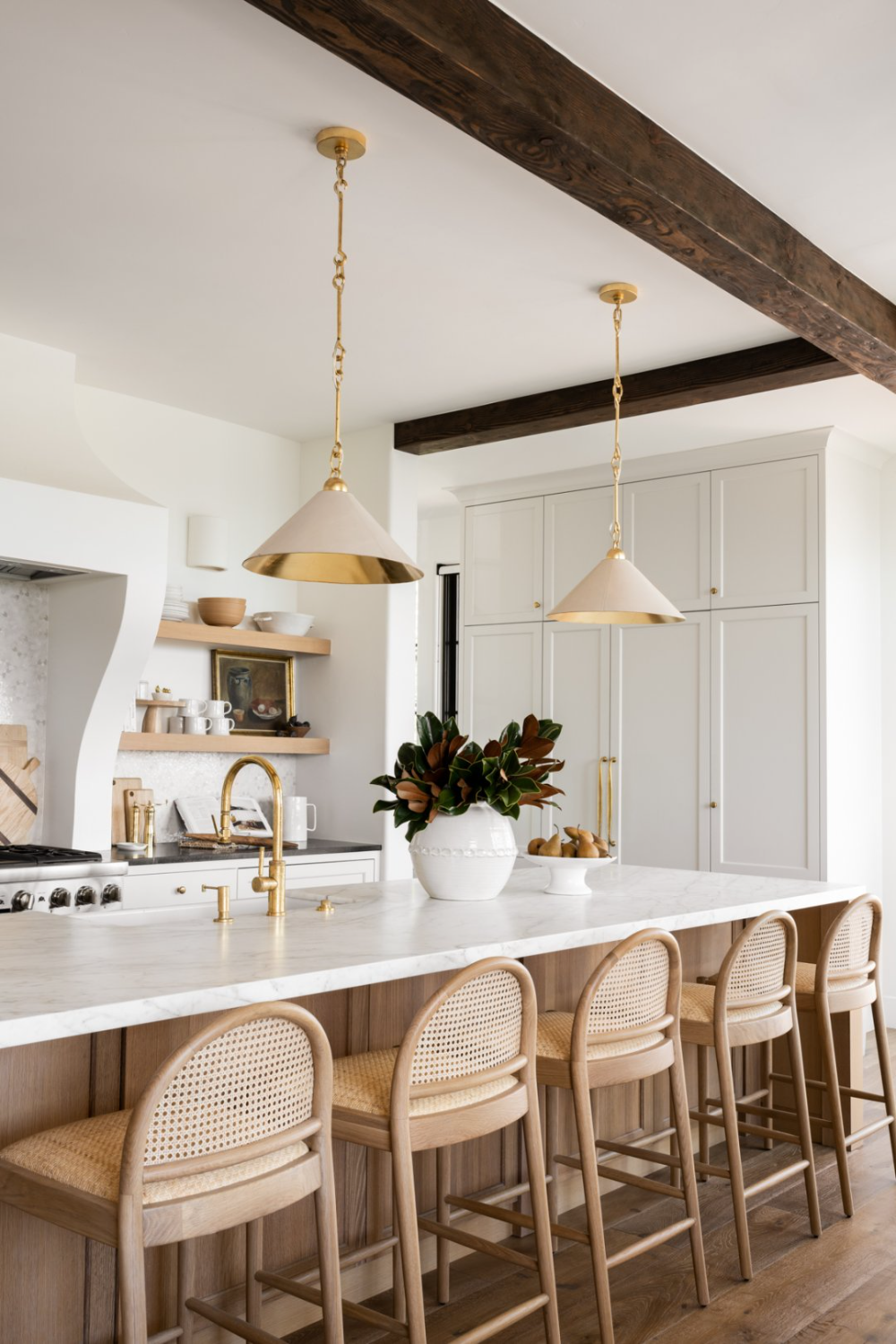 luxury breakfast bar/island in white kitchen with gold details, oak floors and island unit, marble countertops and wicker bar stools