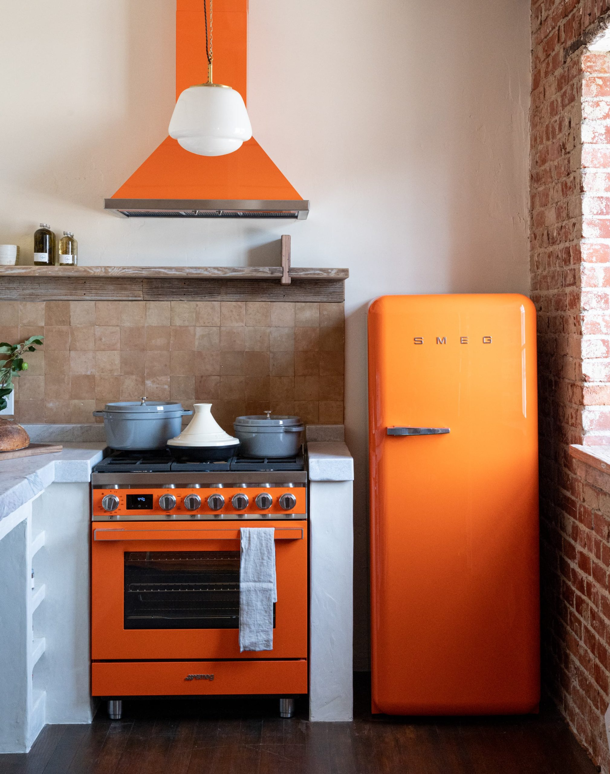 Bright orange glossy retro fridge, stove and extractor fan in kitchen