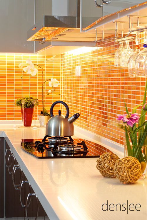 Bright orange mosaic kitchen backsplash, grey cabinetry, white countertop 