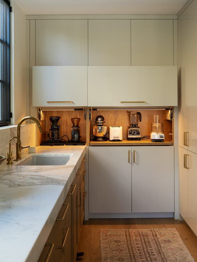 cabinetry with secret compartment for appliances in white kitchen 