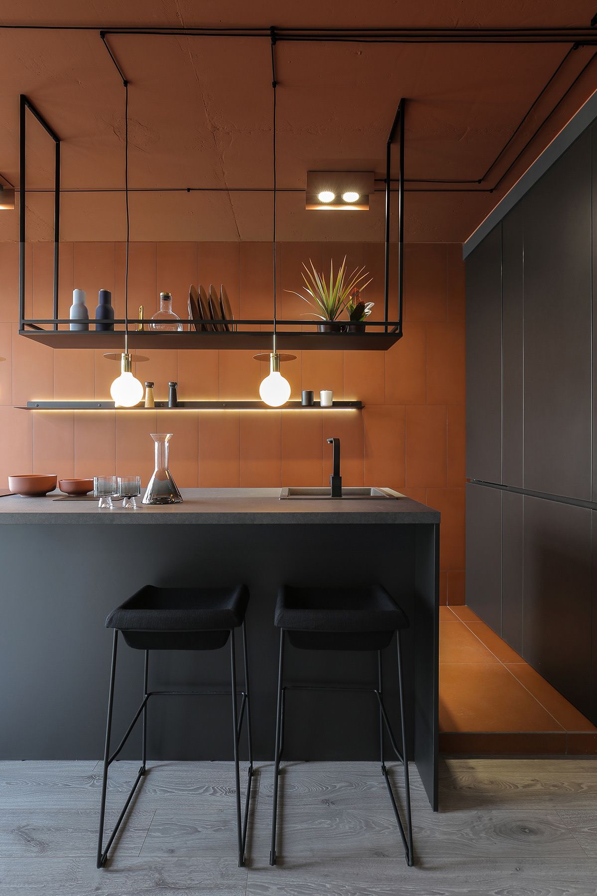 siena coloured floor, wall and ceiling in modern kitchen with matte black cabinetry