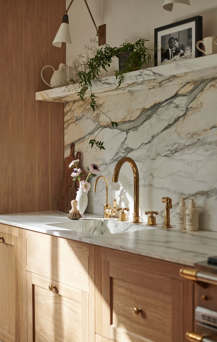 marble backsplash and countertop, gold tap, oak cabinets, fresh greenery decorations