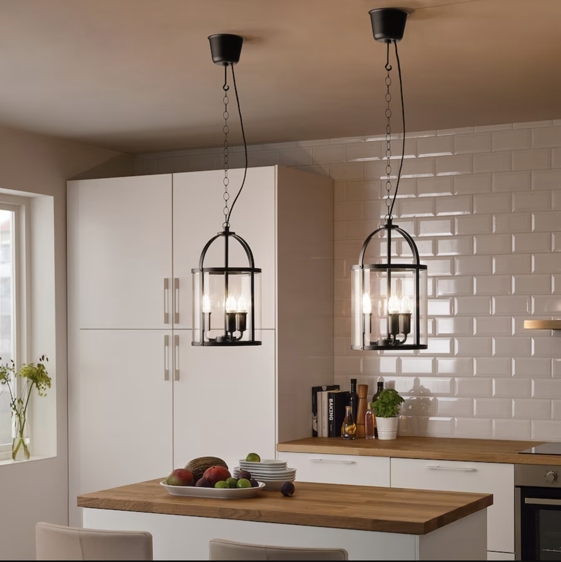 black iron and glass pendant lights candle style over island in white kitchen with oak countertops