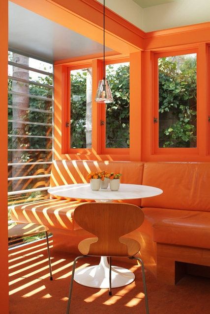 orange window casing and floor beam and orange sofa cushions in kitchen area.