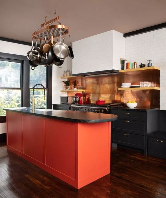 Black and white kitchen with orange island and bronze details