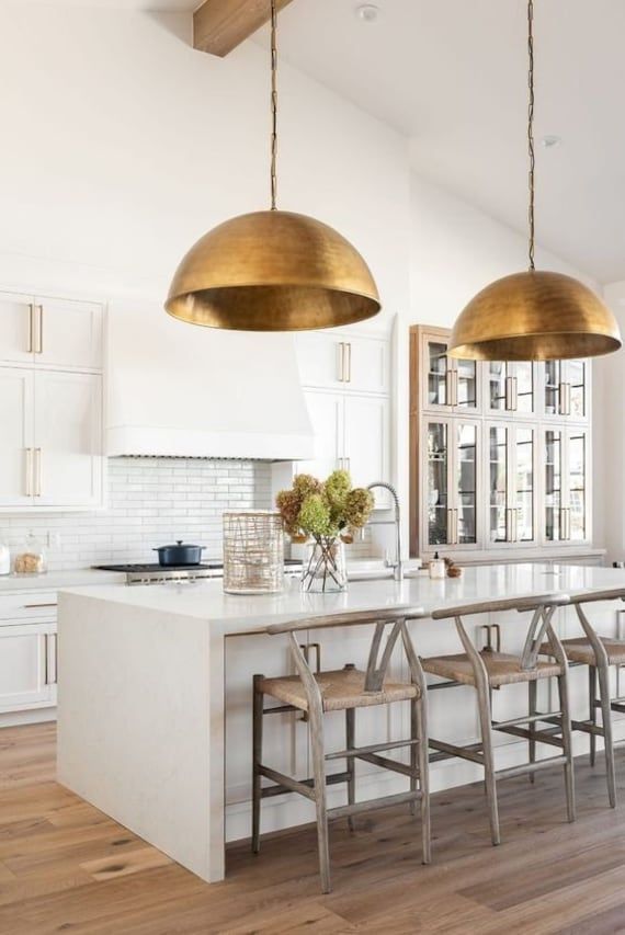 white kitchen with large round brass light pendants over island